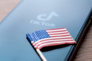 A small American flag and a smartphone which displays the TikTok logo and name.