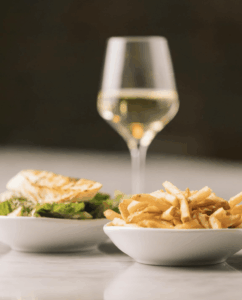 Caesar salad, french fries and a glass of wine