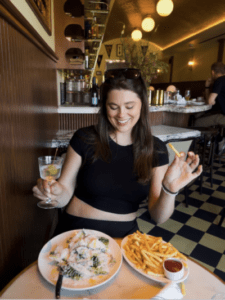 Olivia Maher, founder of girl dinner, enjoying a caesar salaa, french fries and a martini.