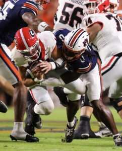 An Auburn defender tackles a Georgia ball carrier, bringing him down as players from both teams converge around the play.